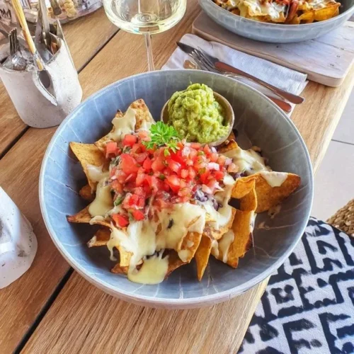 Assiette de nachos garnis de guacamole crémeux et salsa fraîche.