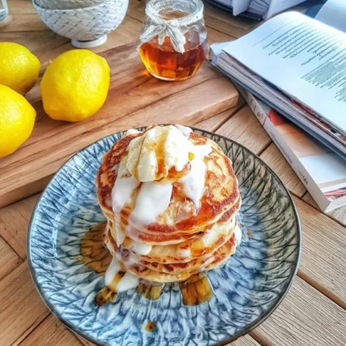 Pancakes à la Ricotta et Citron sur une assiette garnis de zestes de citron