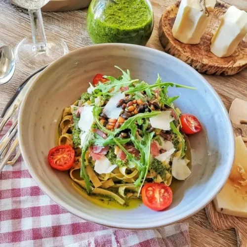Plat de tagliatelles fraîches au pesto de roquette, garnies de parmesan.